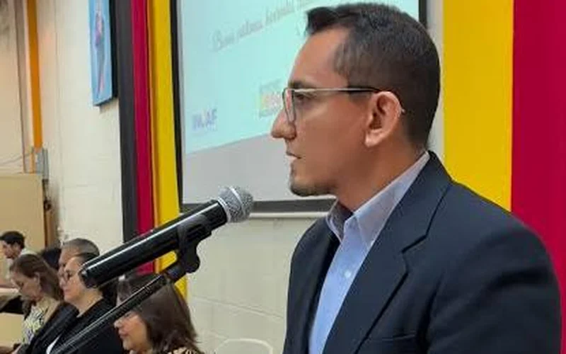 Hombre con anteojos y saco azul oscuro habla en un podio frente a un micrófono; al fondo, una pantalla con el logo de INCAF y asistentes sentados