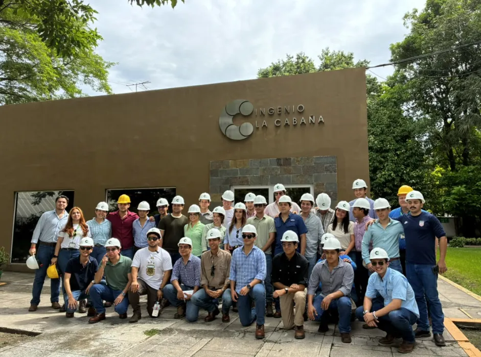Estudiantes de Agronegocios de la Universidad Zamorano con cascos de seguridad frente al Ingenio La Cabaña en El Salvador