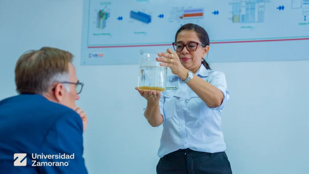 Profesora de Universidad Zamorano muestra una muestra de agua a un representante de la Embajada de Estados Unidos en la planta AguaClara Reach