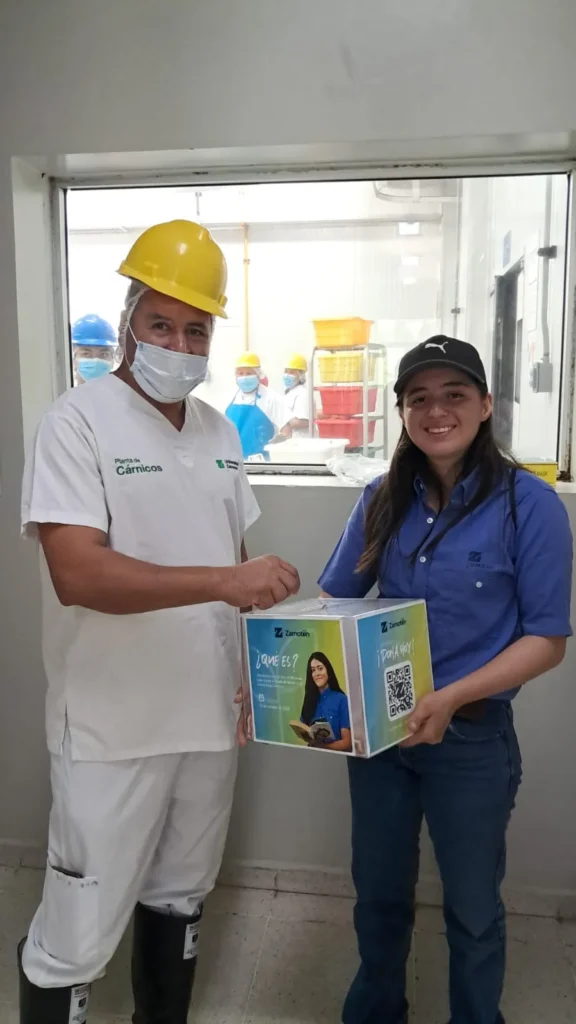 Colaborador de una planta de Universidad Zamorano deposita su aporte en la caja de Zamotón 2026 junto a una estudiante